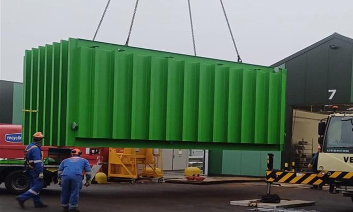 A green vacuum cooler being lifted by a crane off the truck into its place onsite.